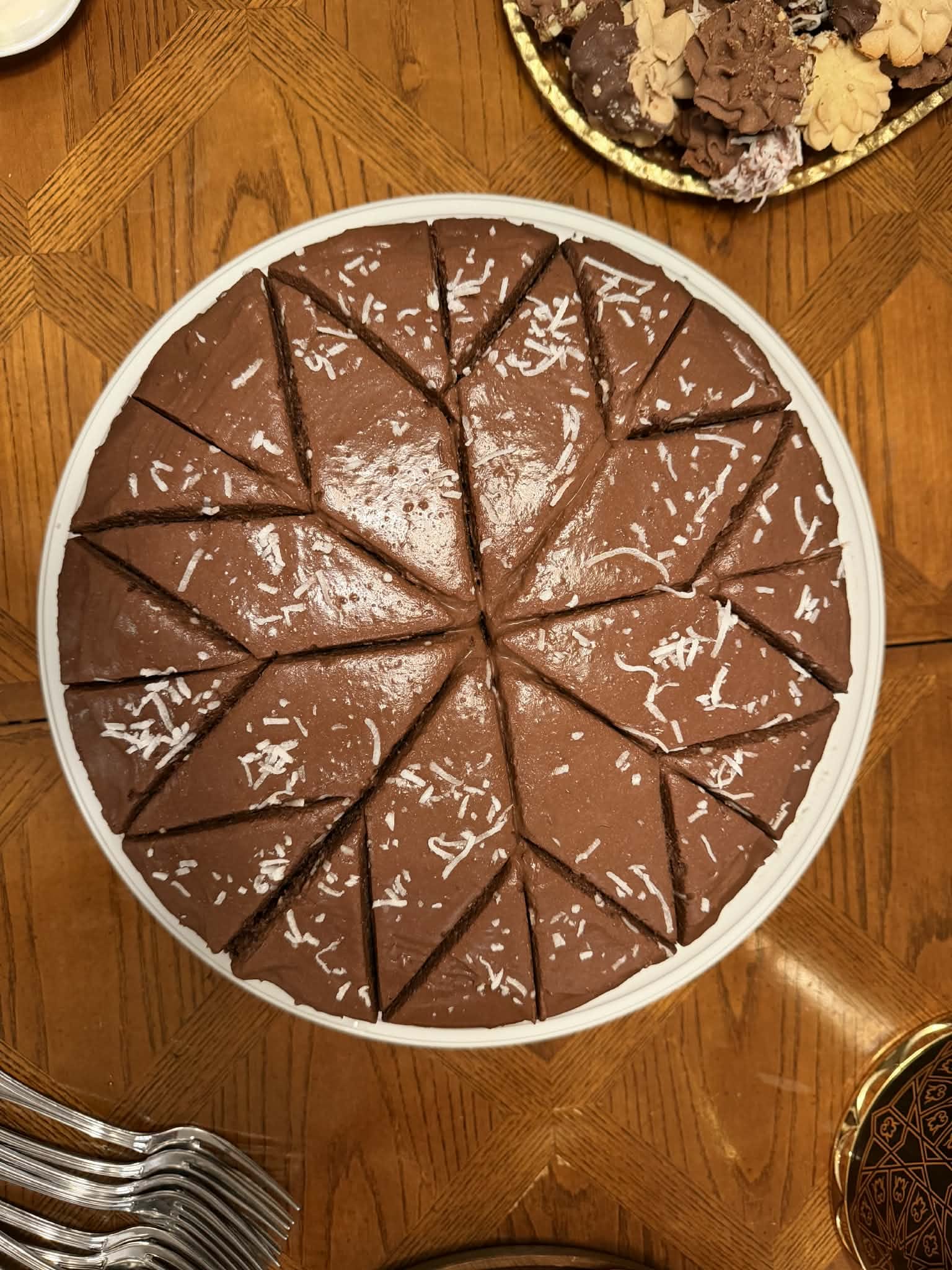 Round chocolate cake sliced into triangles — chocolate frosting lightly topped with shredded coconut